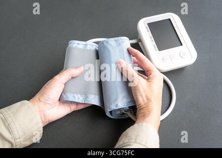 Woman reaching out to blood pressure monitor device. Close up view. Stock Photo