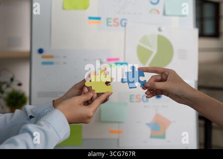 ESG Puzzle. Hands connecting pieces symbolizing teamwork in sustainability efforts. Stock Photo