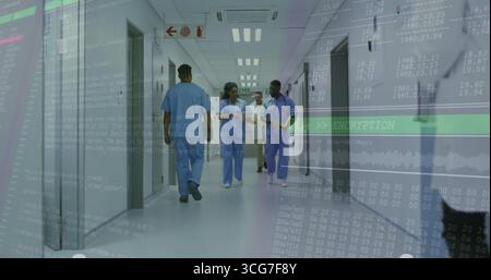 Walking staff wearing scrubs discussing patient charts in hospital corridor with encryption overlay Stock Photo