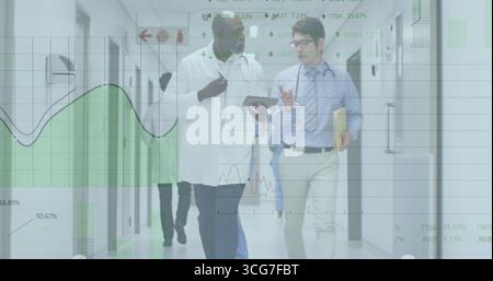 Walking two doctors in lab coat and tie along hospital corridor, reviewing tablet data overlays Stock Photo