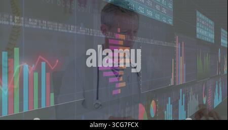 Interacting male doctor wearing lab coat, stethoscope using digital display in clinic, with charts Stock Photo