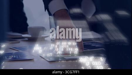 Displaying hand in suit tracing printed charts and graphs at meeting table with binary code overlay Stock Photo