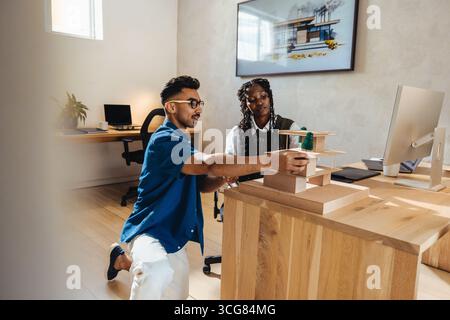 Two young professionals discussing a modular architectural model and working in a creative office. The environment showcases modern design and teamwor Stock Photo
