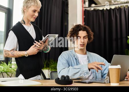 Two young professionals collaborate in a vibrant office environment, focused and engaged. Stock Photo