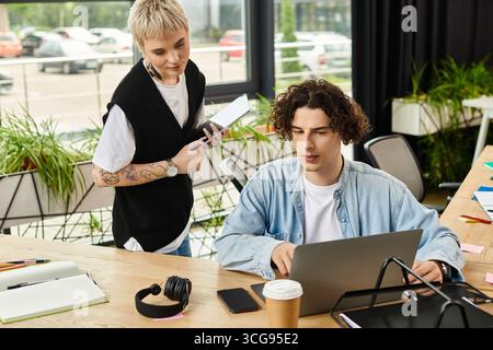Two young professionals engage in a collaborative work session, sharing ideas and tools. Stock Photo