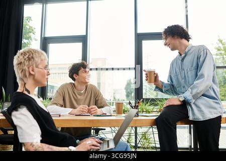 Three young individuals share ideas and laughter while working together in a stylish office. Stock Photo