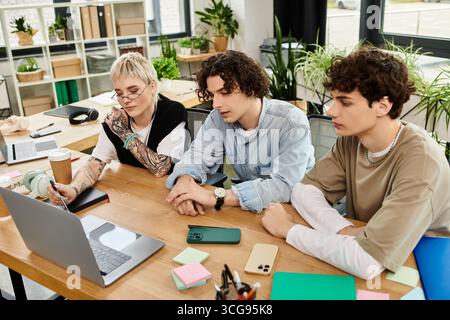 Three young individuals engage in focused discussion while collaborating on a project at the office. Stock Photo