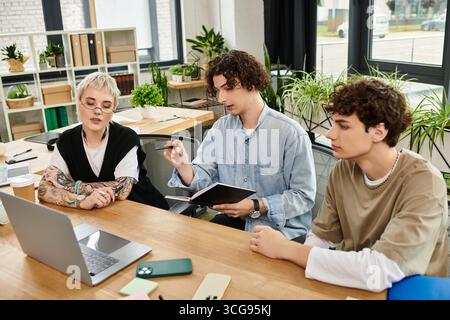 Three young professionals engage in a collaborative discussion at an office workspace. Stock Photo