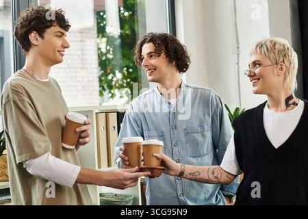 Three young individuals share a moment of teamwork and connection while enjoying coffee together. Stock Photo