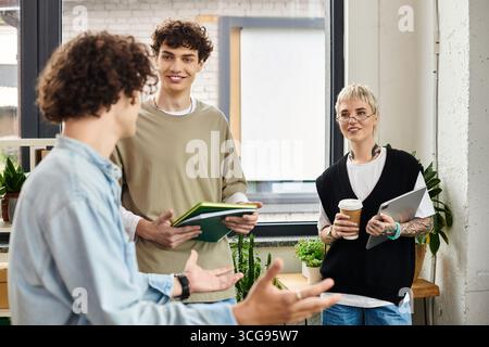 Three young individuals share ideas and insights while working together in a bright office space. Stock Photo