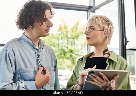 Two young people discuss ideas and perspectives in a modern office. Stock Photo