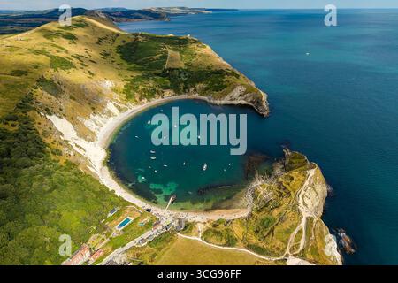 Aerial view of Lulworth Cove with turquoise waves crashing against ...