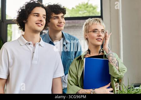 Three young people share ideas while collaborating in a modern office. Stock Photo