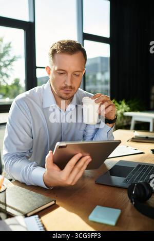 Confident young professional engages with a tablet while enjoying a beverage in an office. Stock Photo