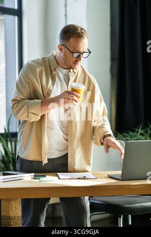 Young professional reviews documents with a morning drink at his workspace. Stock Photo