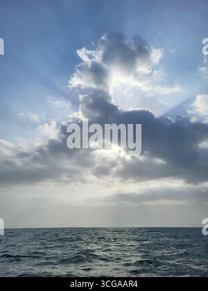 Sunbeams breaking through dramatic clouds over the open sea near Shidvar Island in southern Iran. Stock Photo
