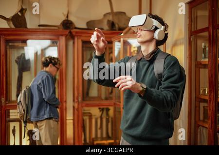 Young Caucasian Man Experiencing Virtual Reality in Museum Exhibition Space Stock Photo