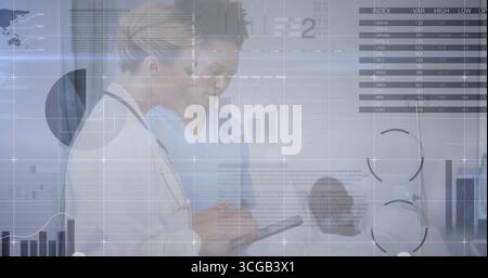 Senior physician and nurse reviewing medical data in clinic hallway, using tablet and stethoscope Stock Photo