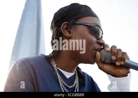 Young Black Man Singing into Microphone Outdoors Wearing Sunglasses and Chains Stock Photo