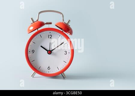 Red alarm clock on blue background. Close up. Stock Photo