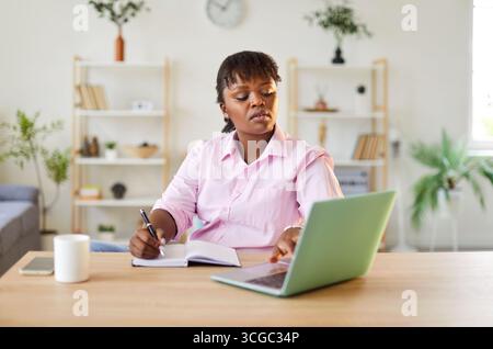 Serious African American woman writer working on new book and doing research on laptop Stock Photo