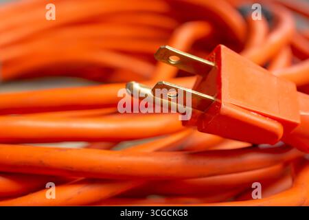 A closeup view of the prongs on a plug of an orange extension cord. Stock Photo
