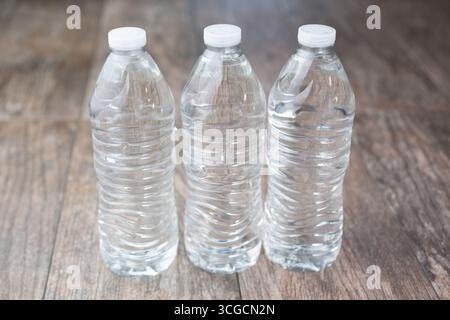 A view of three plastic water bottles with no labels on a wooden surface. Stock Photo