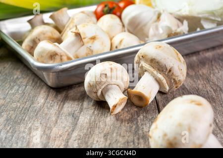 A closeup view of a metal tray featuring white button mushrooms, in a still life setting. Stock Photo