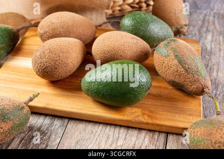 A view of several unripened avocados on a wood cutting board. Stock Photo