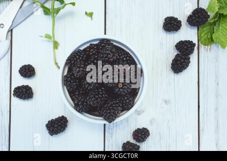 A top down view of a bowl of blackberries, on a wooden table surface. Stock Photo