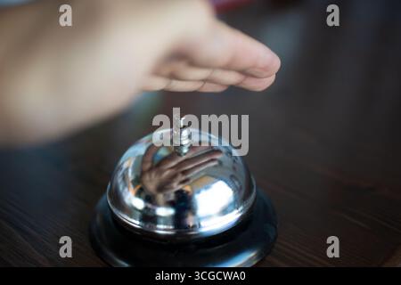 A view of a hand hovering over a service bell, ready to ask for service. Stock Photo