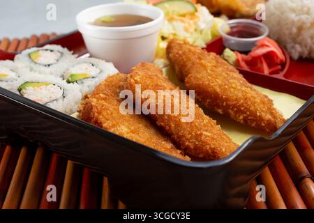 A closeup view of a bento box, featuring California rolls and tofu cakes. Stock Photo
