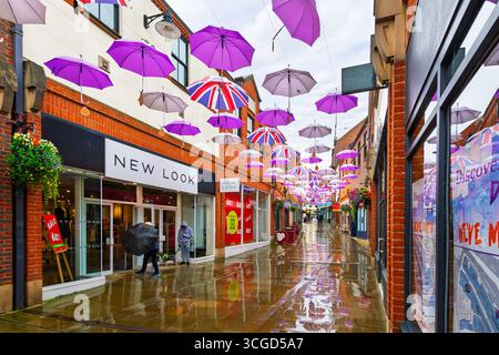 A colorful umbrella sky display above a shopping street on an overcast rainy day in the historic town of Durham, England. Stock Photo