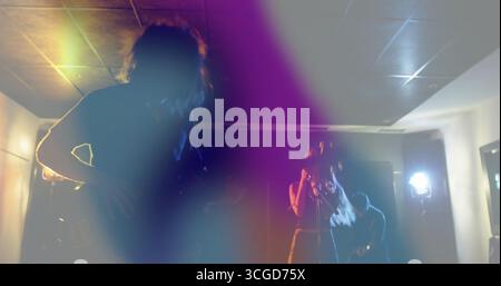 Performing musicians strumming guitars and singing on stage under colored lights, with mic stand Stock Photo