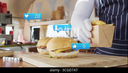 Vendor in striped apron placing items in box at food truck, with cheeseburgers board social icons Stock Photo