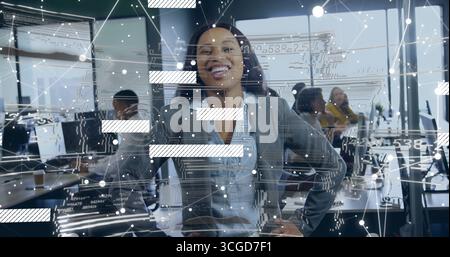 Smiling businesswoman standing with hands on hips in open-plan office, digital overlay graphics Stock Photo