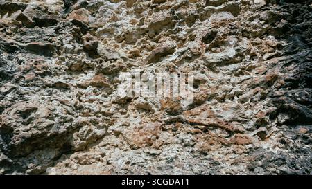 Close-up of an ancient, weathered rock surface featuring a rich, rough texture in earthy tones. Ideal for backgrounds, natural themes, or geological s Stock Photo