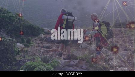 Trekking middle-aged hikers climbing rocky trail at ridge, with backpacks, sleeping pad and poles Stock Photo