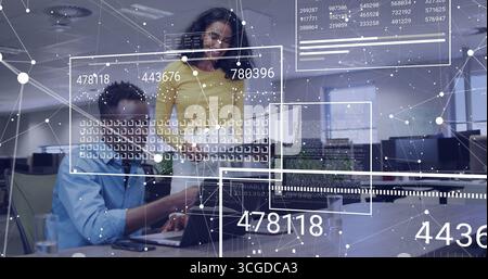 Collaborating technology experts examining network data overlays on laptop in open-plan office Stock Photo