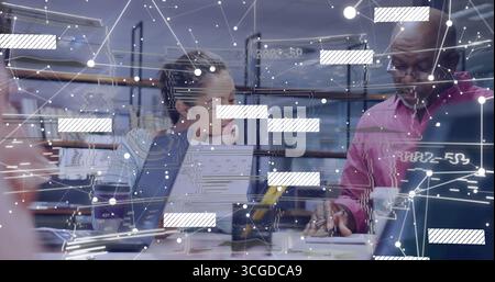 Collaborating group of four professionals analyzing data with laptops at office, with AR overlay Stock Photo