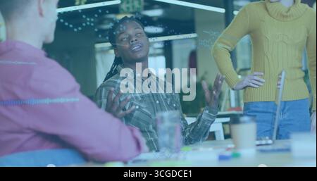 Gesturing Black developer wearing green plaid shirt presenting at tech office with laptop, markers Stock Photo