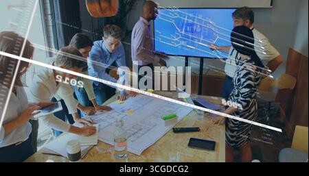 Reviewing team of seven colleagues analyzing blueprint and monitor at conference room, with laptops Stock Photo