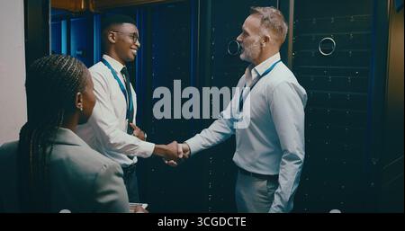 Agreement, handshake and welcome with people in server room for network administration deal. Cybersecurity, meeting and thank you with team shaking Stock Photo