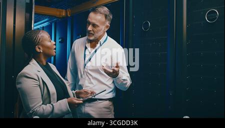 Tablet, team and people in server room for talking, cloud computing or IT training with intern. Collaboration, tech and engineer in data center for Stock Photo