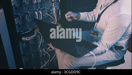 Fixing, cables and hands with laptop, server room and network engineering with tech and electrician. Data center, technician and person with app for Stock Photo