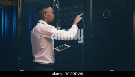 Administration, cybersecurity and tablet with black man in server room for network maintenance. App, firewall and mainframe with tech support employee Stock Photo
