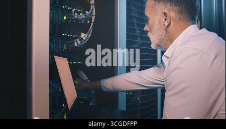 Cable, laptop and technician man in server room for cyber security, software update and database system. Programmer, developer and cybersecurity with Stock Photo