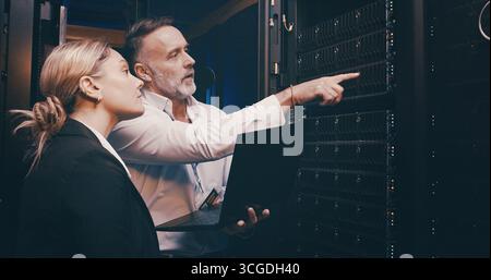 Laptop, pointing and team of engineers in control room for technical support, database or cybersecurity. Computer, collaboration and people with Stock Photo
