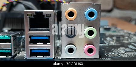 Close-up of a computer motherboard's rear I/O panel, showcasing blue USB 3.0 ports, an Ethernet port, and a full set of color-coded 3.5mm audio jacks Stock Photo
