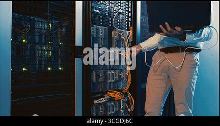 Hands, laptop and system test in server room for diagnostics, troubleshooting and maintenance. Engineer, cables and tech in data center for network Stock Photo